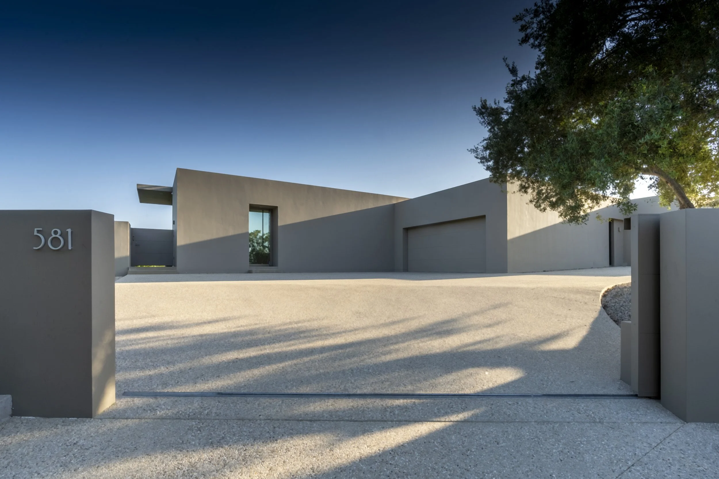 Modern minimalist exterior of Toro Canyon Residence by The Warner Group Architects, Inc., featuring clean architectural lines, a sleek facade, and a private gated entrance.