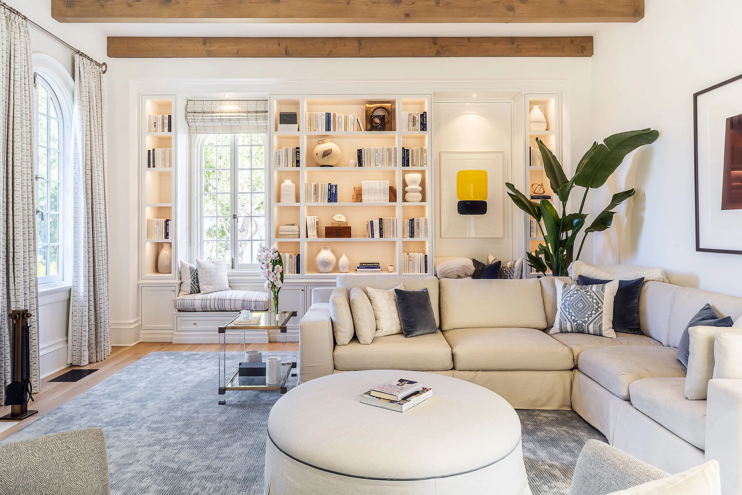 Bright and cozy living room with built-in bookshelves, large sectional sofa, and modern decor, designed by The Warner Group Architects, Inc.