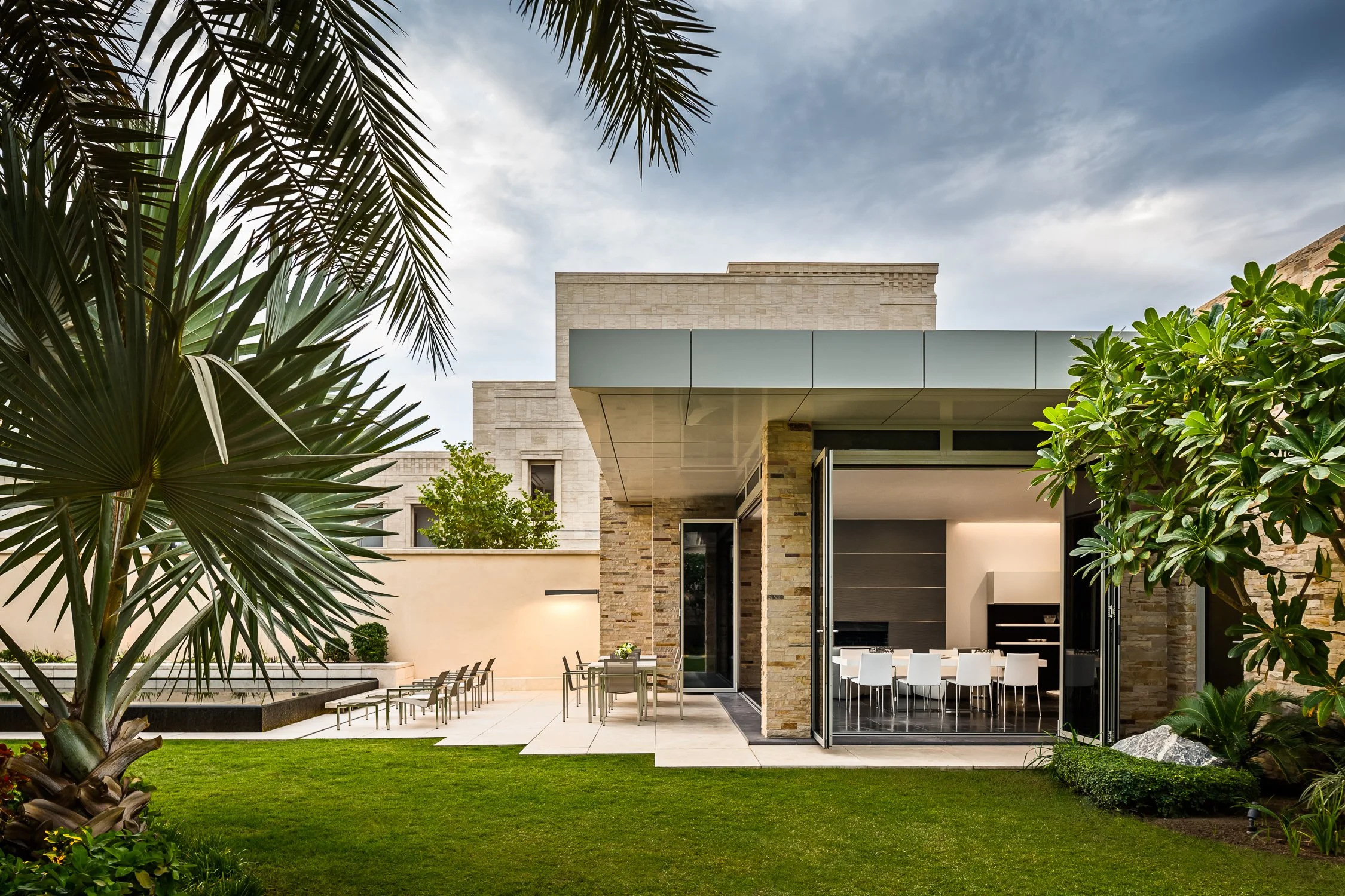 Elegant entrance of a luxury villa surrounded by palm trees, showcasing modern architectural design, Kuwait Estate.