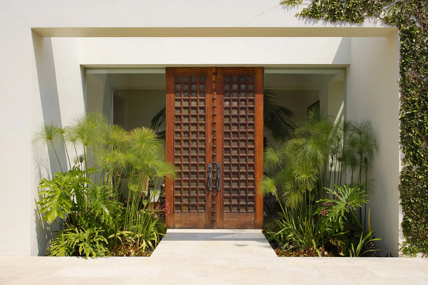 Elegant outdoor entry design featuring large, but easy to open wooden doors and expansive ground to ceiling glass panels.