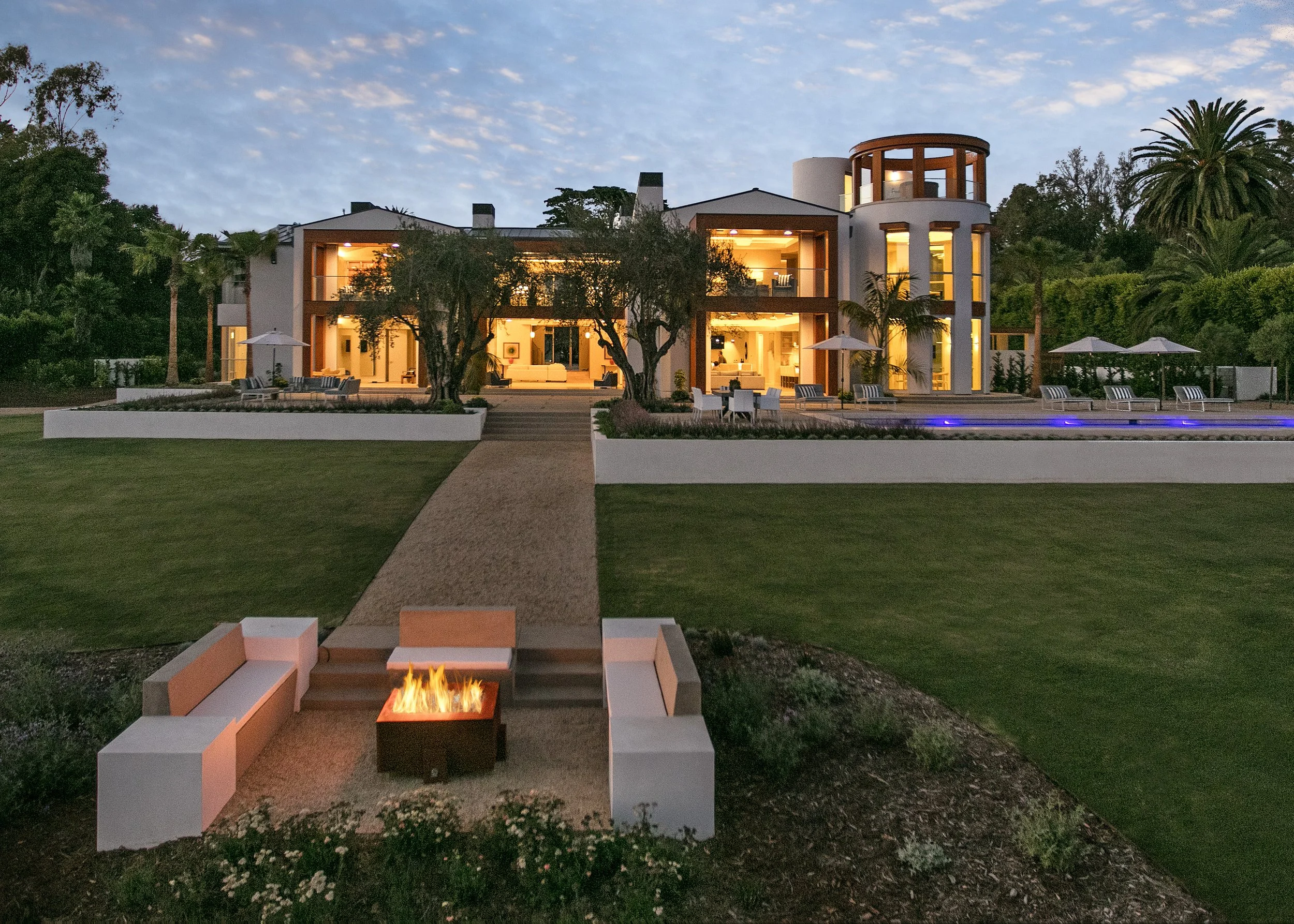 Backyard view of a luxury modern home with a fire pit and pool.
