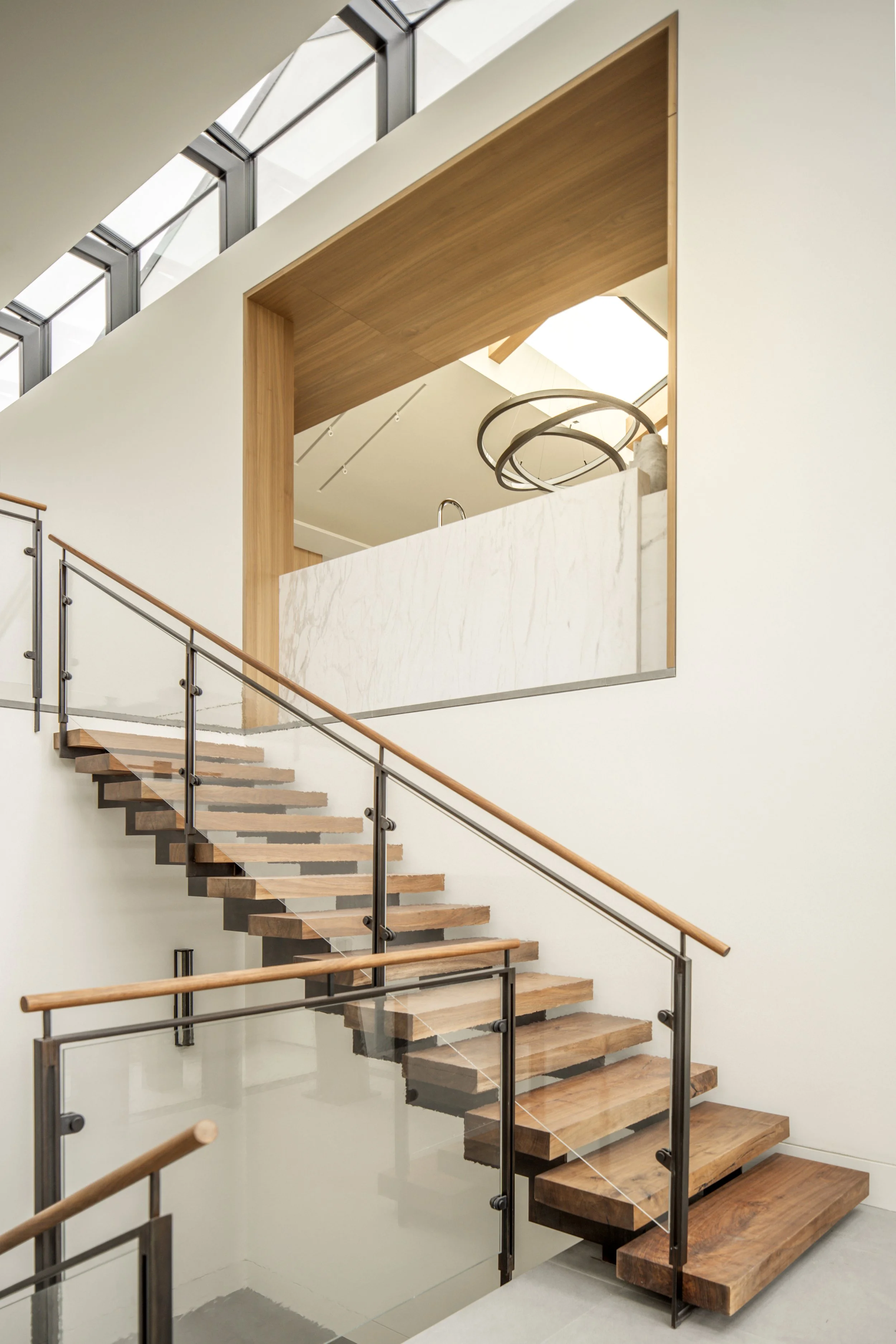 Modern wooden staircase with glass railing in a minimalist interior design.