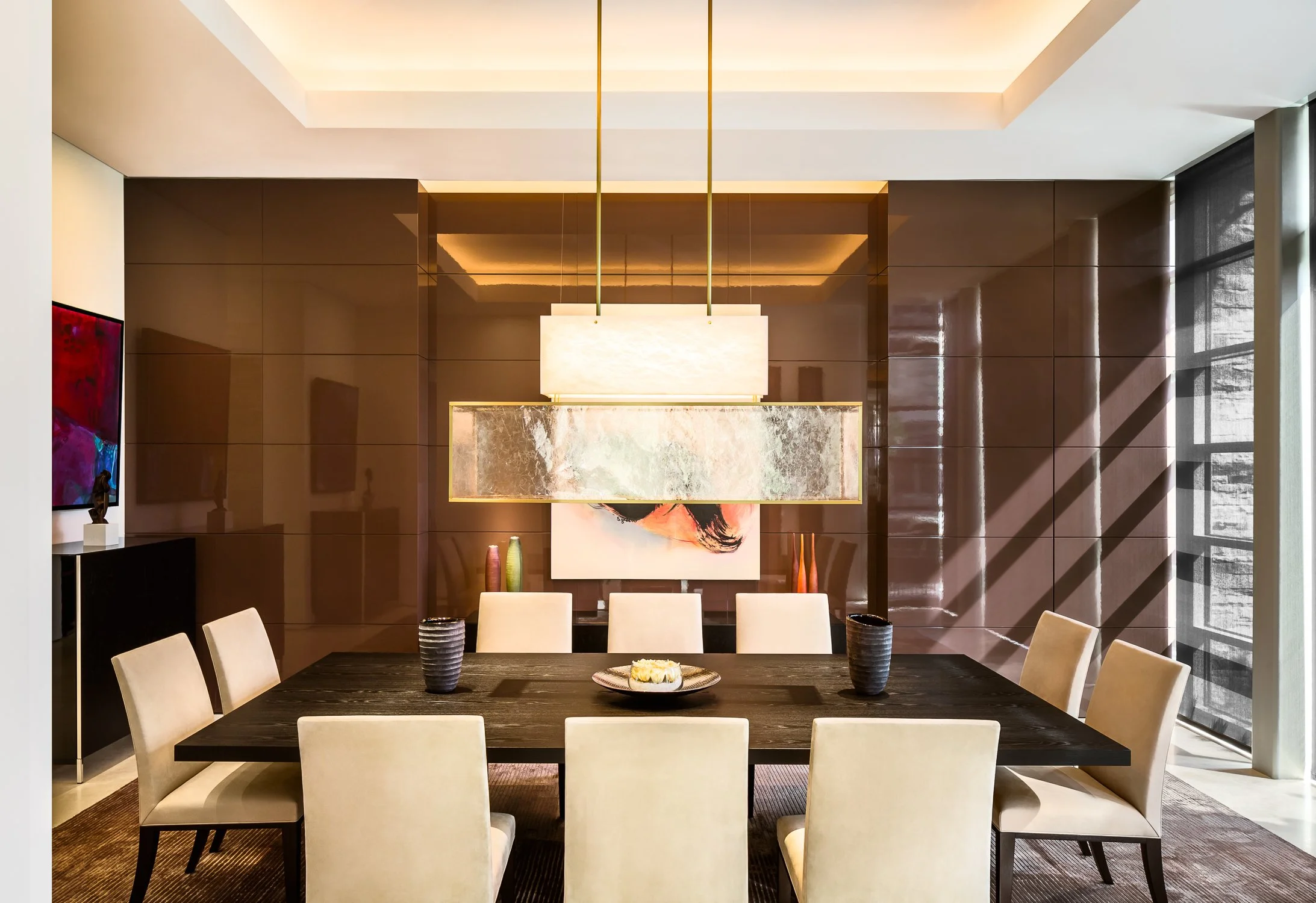 Elegant dining room with modern lighting and a large black table. Featuring elegant contemporary art and chandelier.