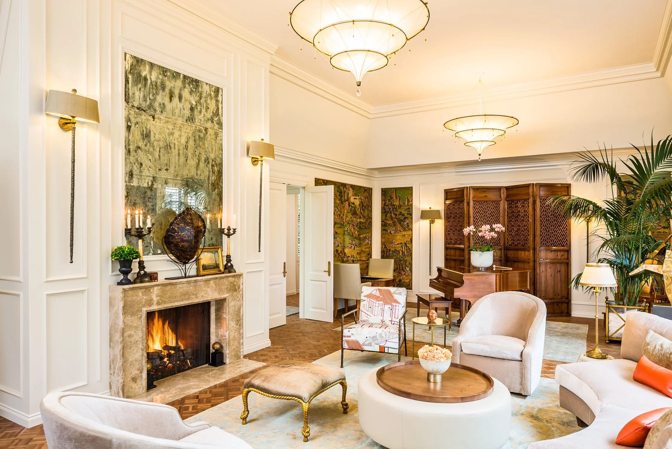 Elegant living room featuring a fireplace, classic armchairs, a grand piano, and wall art at Birnam Wood Residence by The Warner Group Architects, Inc.