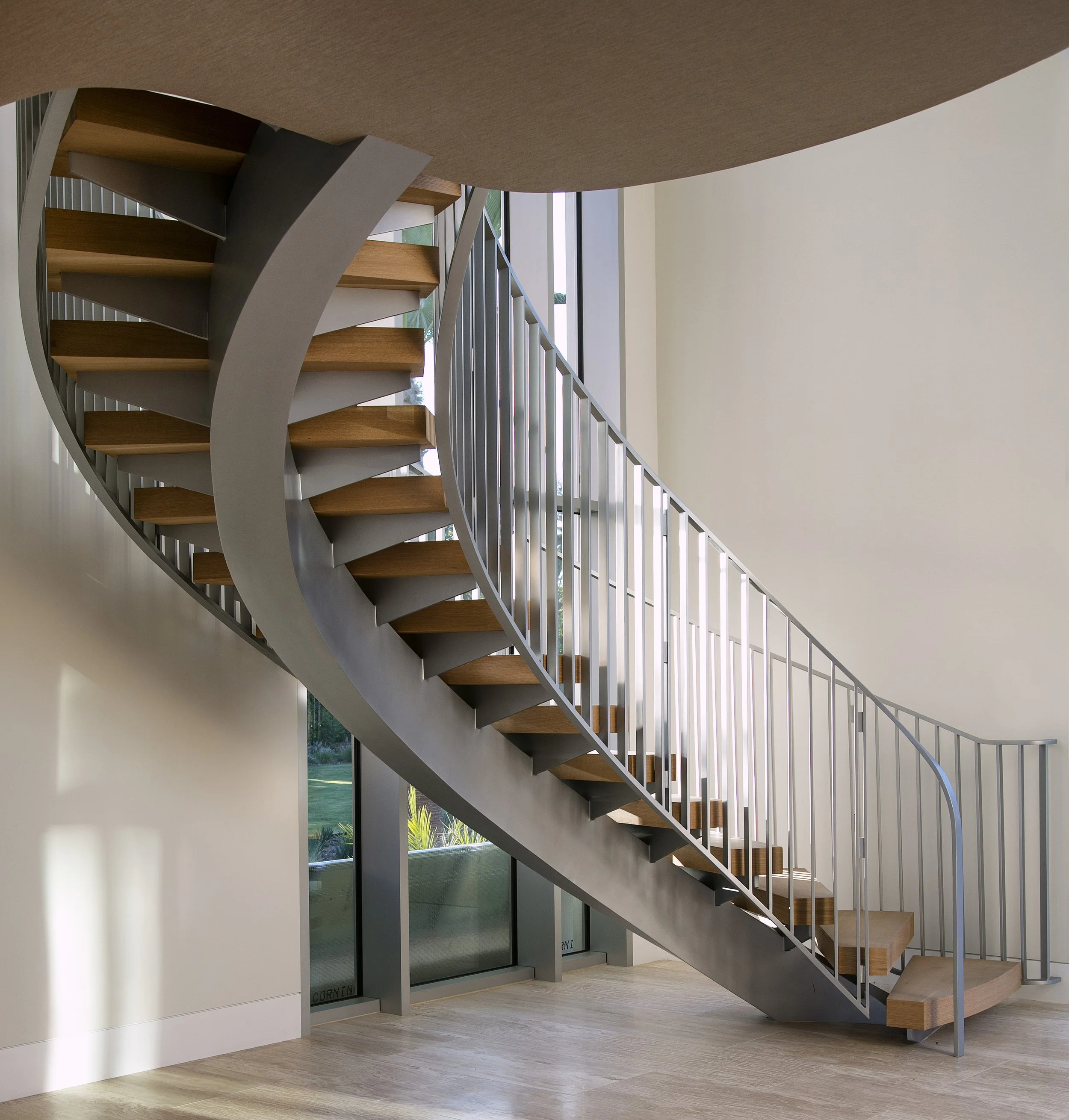Modern spiral staircase with wooden steps and metal railings in a well-lit interior space.