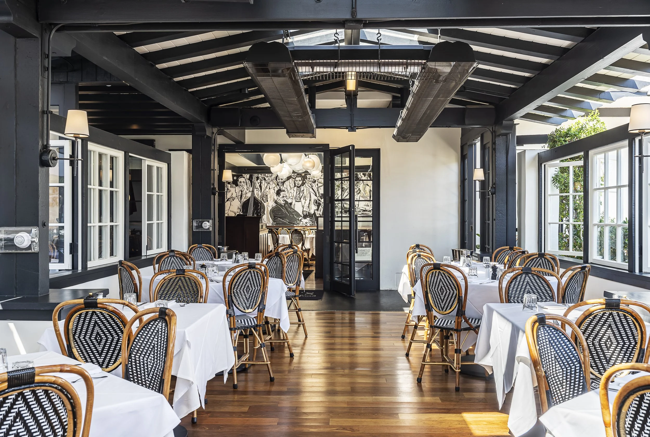 Elegant indoor dining area with large windows and classic black and white wicker chairs.