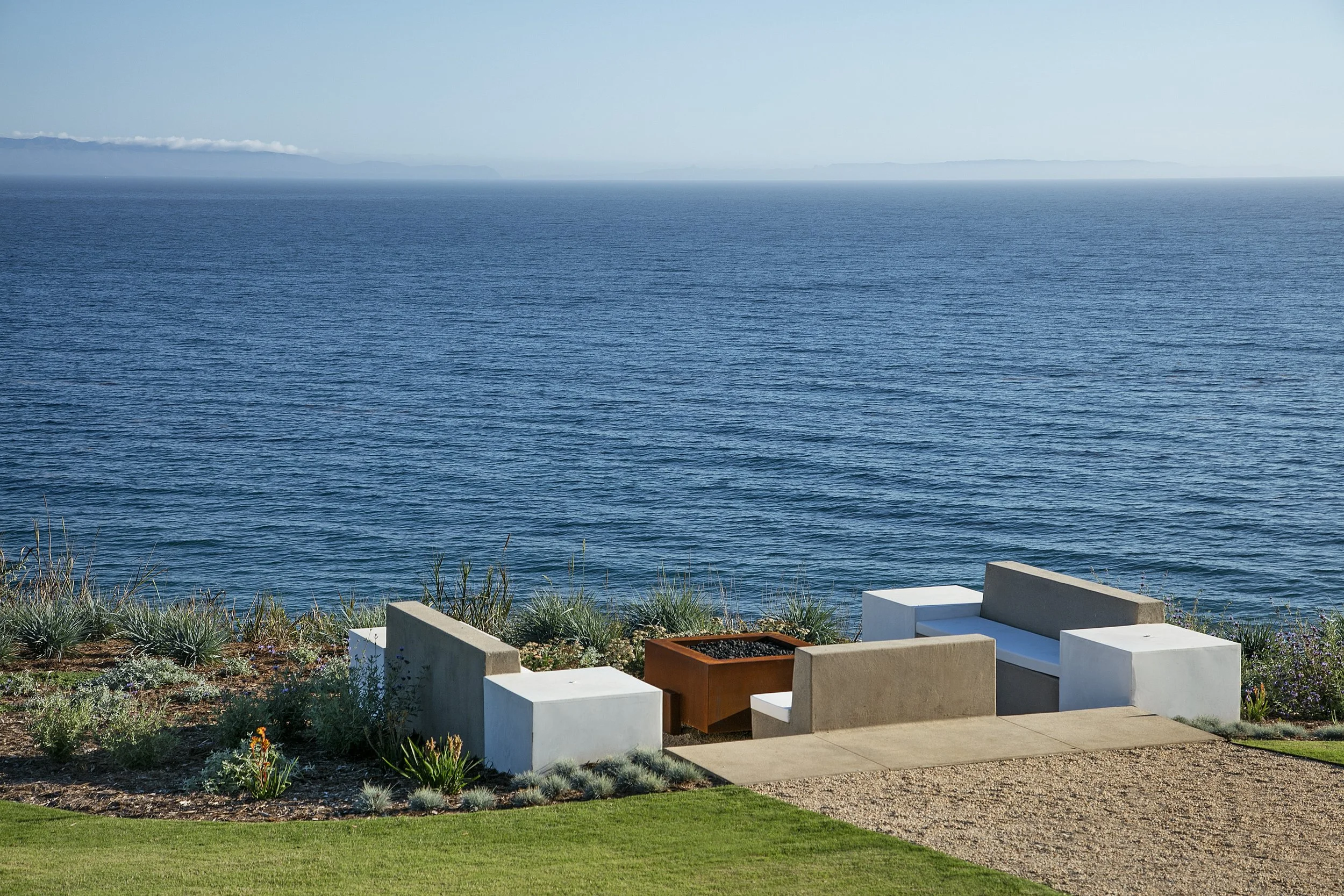 Modern firepit seating area overlooking the ocean with sleek minimalist design in this coastal residence.