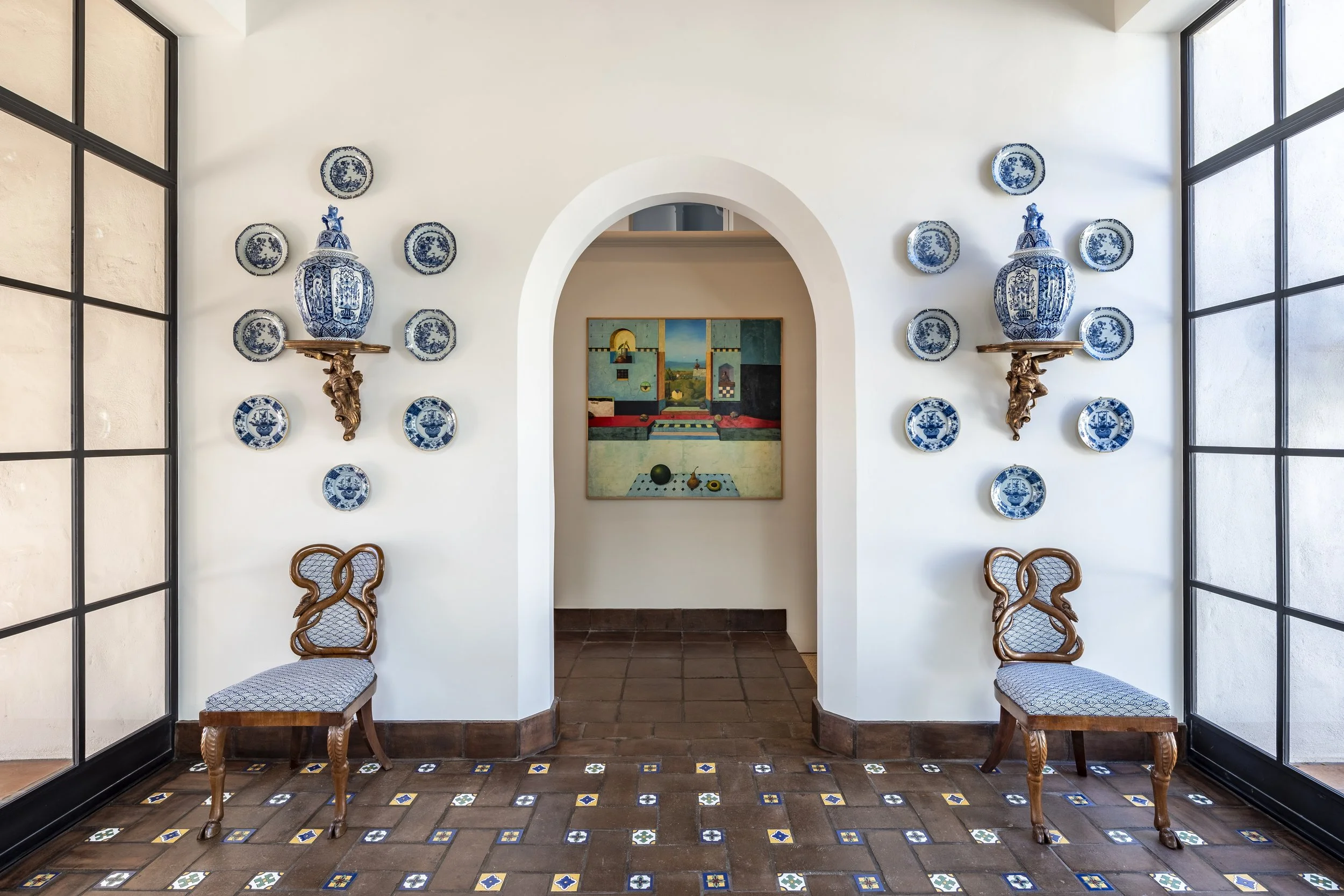 Interior archway with decorative blue and white china plates displayed symmetrically, featuring a framed artwork in the background.
